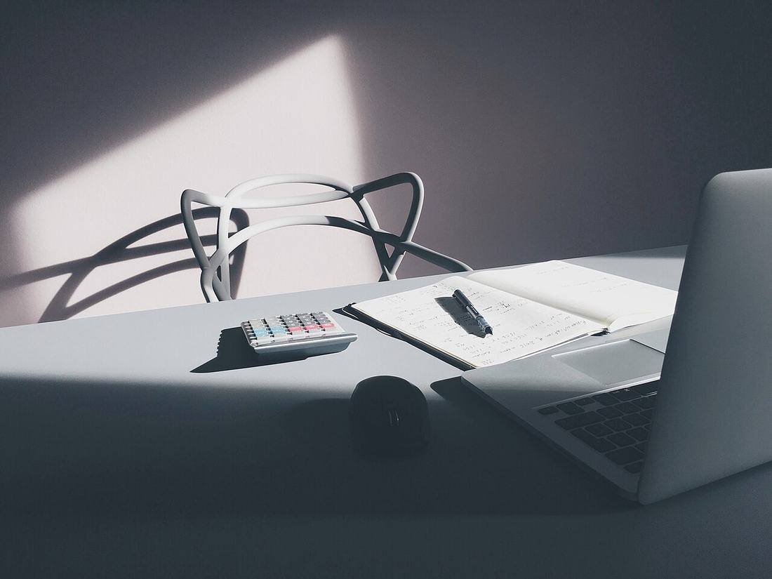 Mesa com laptop, calculadora e caderno